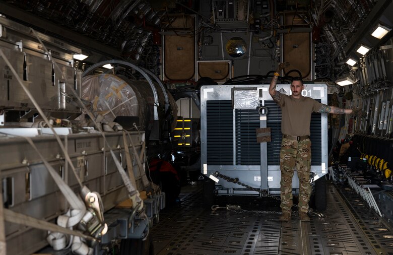 U.S. Air Force Staff. Sgt. Tanner Sullivan, a loadmaster with the 7th Airlift Squadron, marshals equipment, belonging with the 14th Fighter Squadron, Misawa Air Base, Japan, onto a C-17 Globemaster III during Exercise Rainier War 21B in Daegu, South Korea, Nov. 6, 2021. The 62nd Airlift Wing provided transport for the 14th Fighter Squadron from Daegu, South Korea, to Misawa Air Base, Japan. Rainier War is a semi-annual, large readiness exercise led by the 62nd Airlift Wing, designed to train aircrews under realistic scenarios that support full spectrum readiness operations against modern threats and replicate today’s contingency operations. (U.S. Air Force photo by Staff Sgt. Rachel Williams)