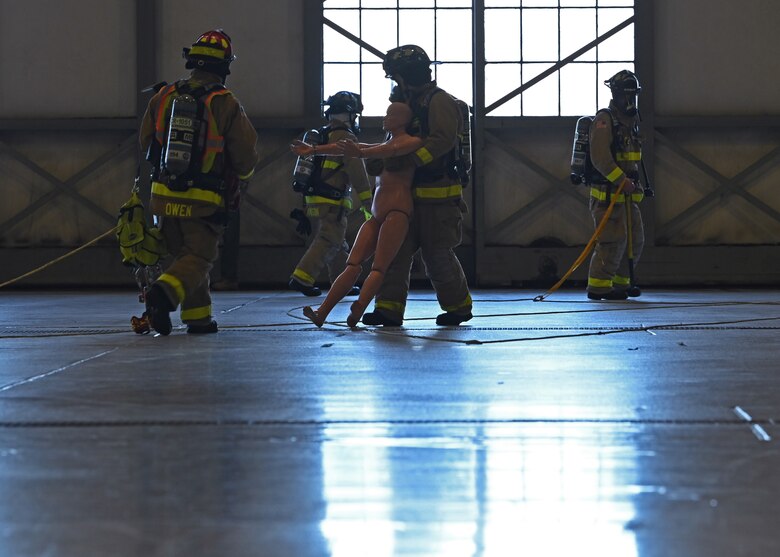 Lewis-McChord Fire and Emergency Services emergency responders carry a simulated victim out of a hangar during Exercise Rainier War 21B at Joint Base Lewis-McChord, Washington, Nov. 8, 2021. Rainier War is a semi-annual, large readiness exercise led by 62nd Airlift Wing, designed to train Airmen under realistic scenarios that support a full spectrum readiness operations against modern threats and replicate today’s contingency operations. (U.S. Air Force photo by Senior Airman Zoe Thacker)