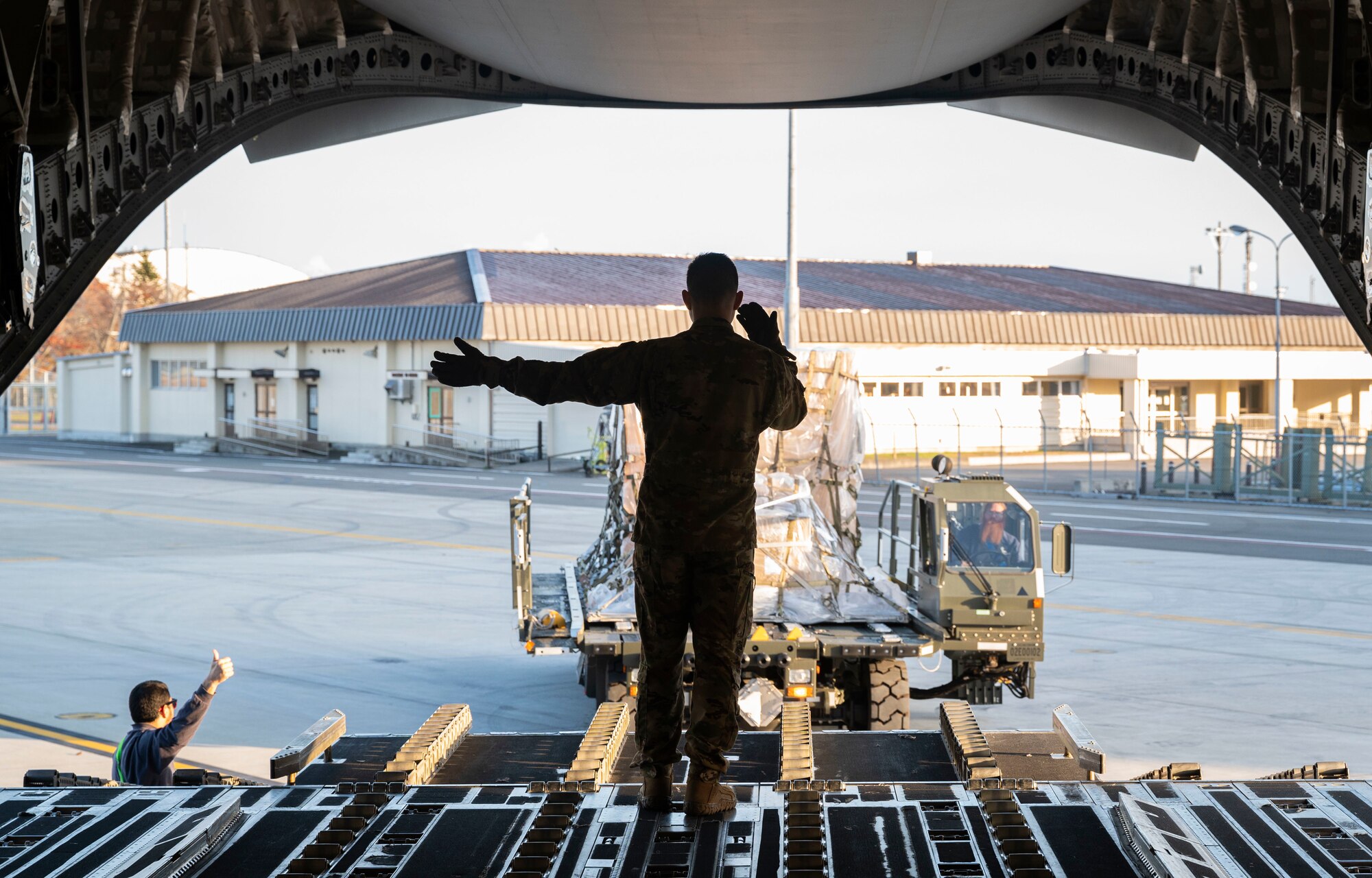 U.S. Air Force Airman First Class Aydan Abad, a loadmaster with the 7th Airlift Squadron, marshals cargo onto a C-17 Globemaster III at Misawa Air Base, Japan, Nov. 6, 2021, during Exercise Rainier War 21B. Rainier War 21B exercised and evaluated the 62nd Airlift Wing’s ability to employ the force and their ability to perform during wartime and contingency taskings in a high-intensity, wartime contested, degraded and operationally limited environment while supporting the contingency operations against a near-peer adversary in the U.S. Indo-Pacific Command area of responsibility. (U.S. Air Force photo by Staff Sgt. Rachel Williams)