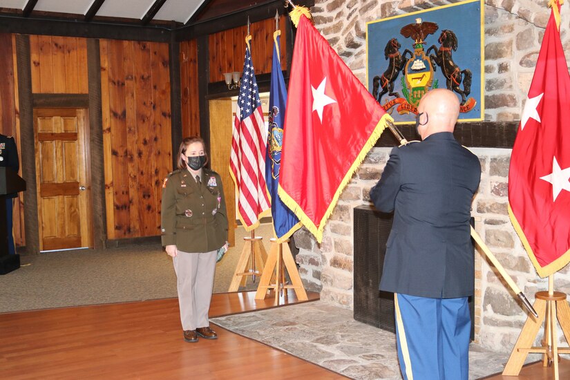 Command Sgt. Maj. Andrew Campbell assists Brig. Gen. Laura McHugh in unfurling her general officer flag during her promotion ceremony on Nov. 6, 2021, at Fort Indiantown Gap, Pa.  McHugh was appointed as the deputy adjutant general - Army on April 1, 2021. (Photo by Lt. Col. Keith Hickox)