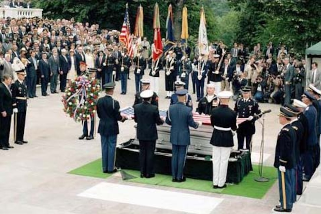 Troops from all of the armed services gather around a coffin.