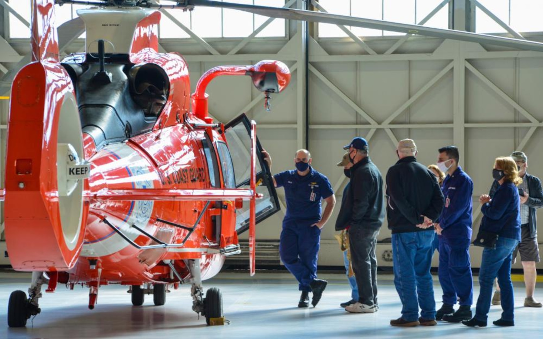 Chief Petty Officer Timothy Willis, a crewmember at the Coast Guard National Capital Region Air Defense Facility, shows an MH-65 Dolphin helicopter to Vietnam veterans from the Coast Guard Cutter Owasco (WHEC-39), a 255-foot high endurance cutter, during a tour of Coast Guard Air Station Washington, Nov. 5, 2021. The veterans were given an air station tour and were presented with official lapel pins commemorating their service and for the 50th anniversary of the Vietnam War. (U.S. Coast Guard photo by Petty Officer 1st Class Tara Molle-Carr/Released)