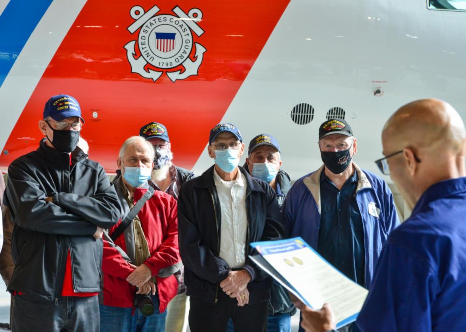 Lt. Cmdr. Jose Mercado, the commemorations program manager at Coast Guard Headquarters in Washington, D.C., reads a certificate to Vietnam veterans from the Coast Guard Cutter Owasco (WHEC-39), a 255-foot high endurance cutter, before presenting them official lapel pins pins commemorating their service and for the 50th anniversary of the Vietnam War at Air Station Washington, Nov. 5, 2021. The veterans were given a tour and spoke with air station personnel about their previous service. (U.S. Coast Guard photo by Petty Officer 1st Class Tara Molle-Carr/Released)