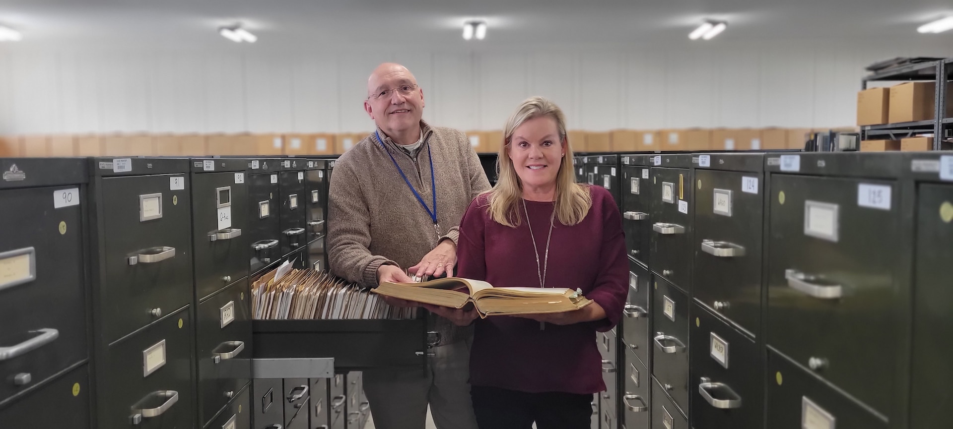 Kathy Boyle, branch manager and Walter Bowman, archivist, pose for a photo surrounded by all the files at the Military records Branch in Frankfort, Ky., Nov. 2, 2021