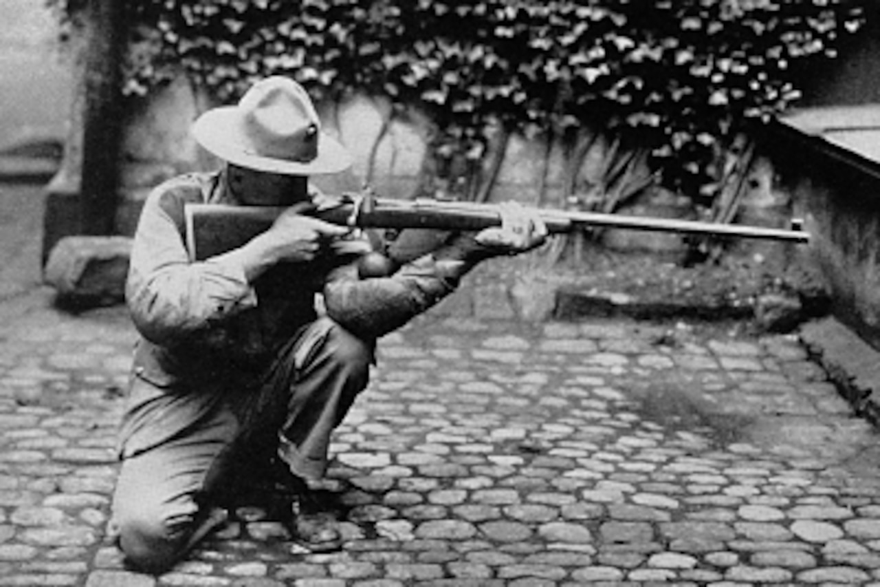 A Marine kneels with a rifle.