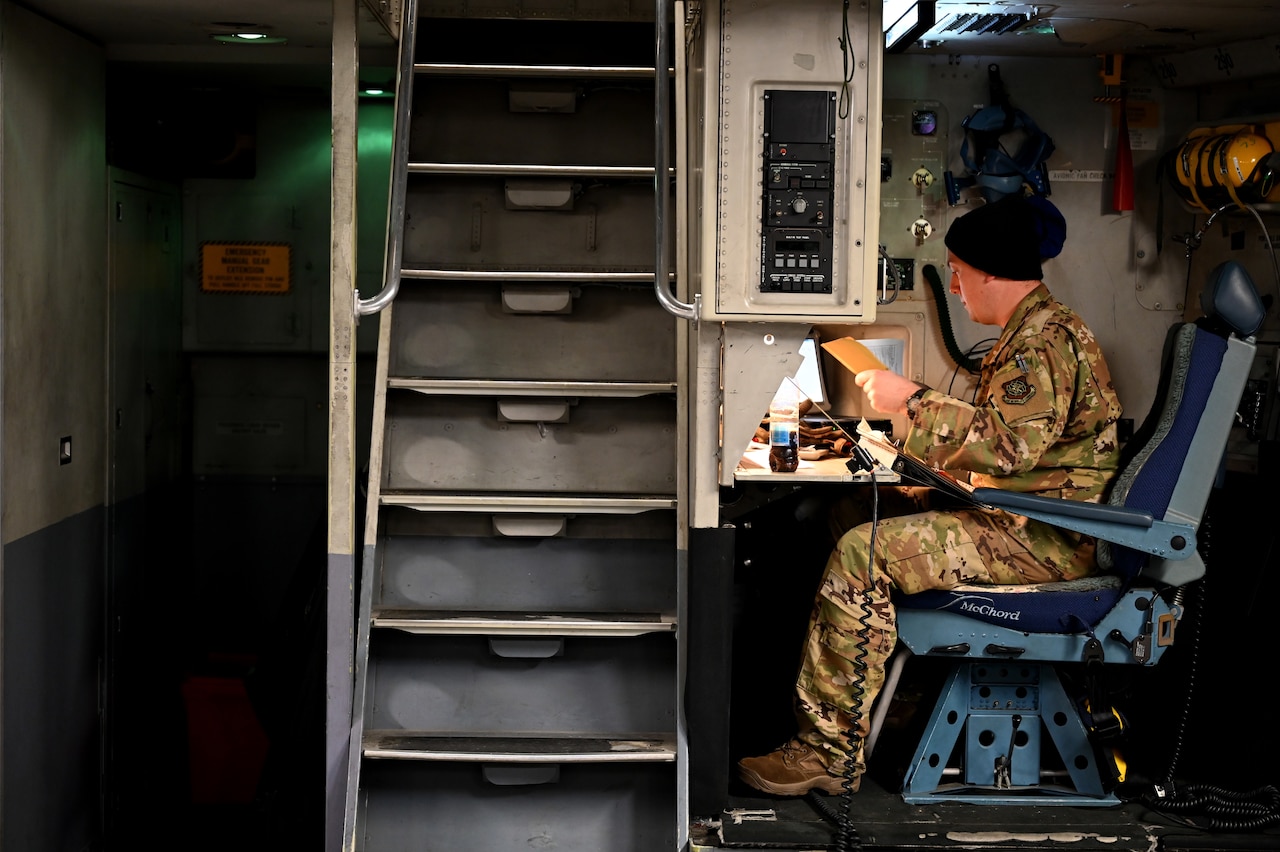 An airman sits at a desk.