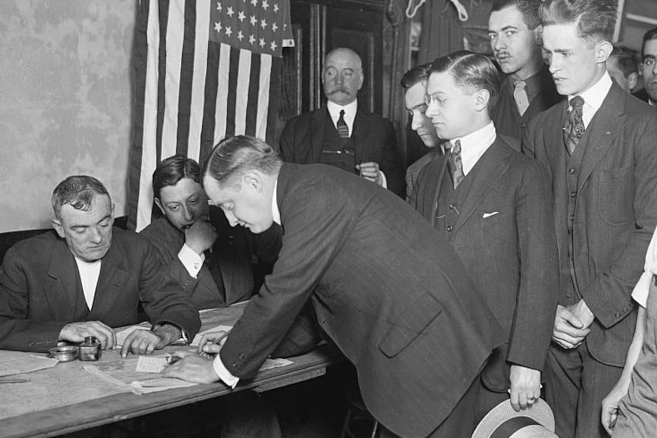 Men stand in a line next to a table.