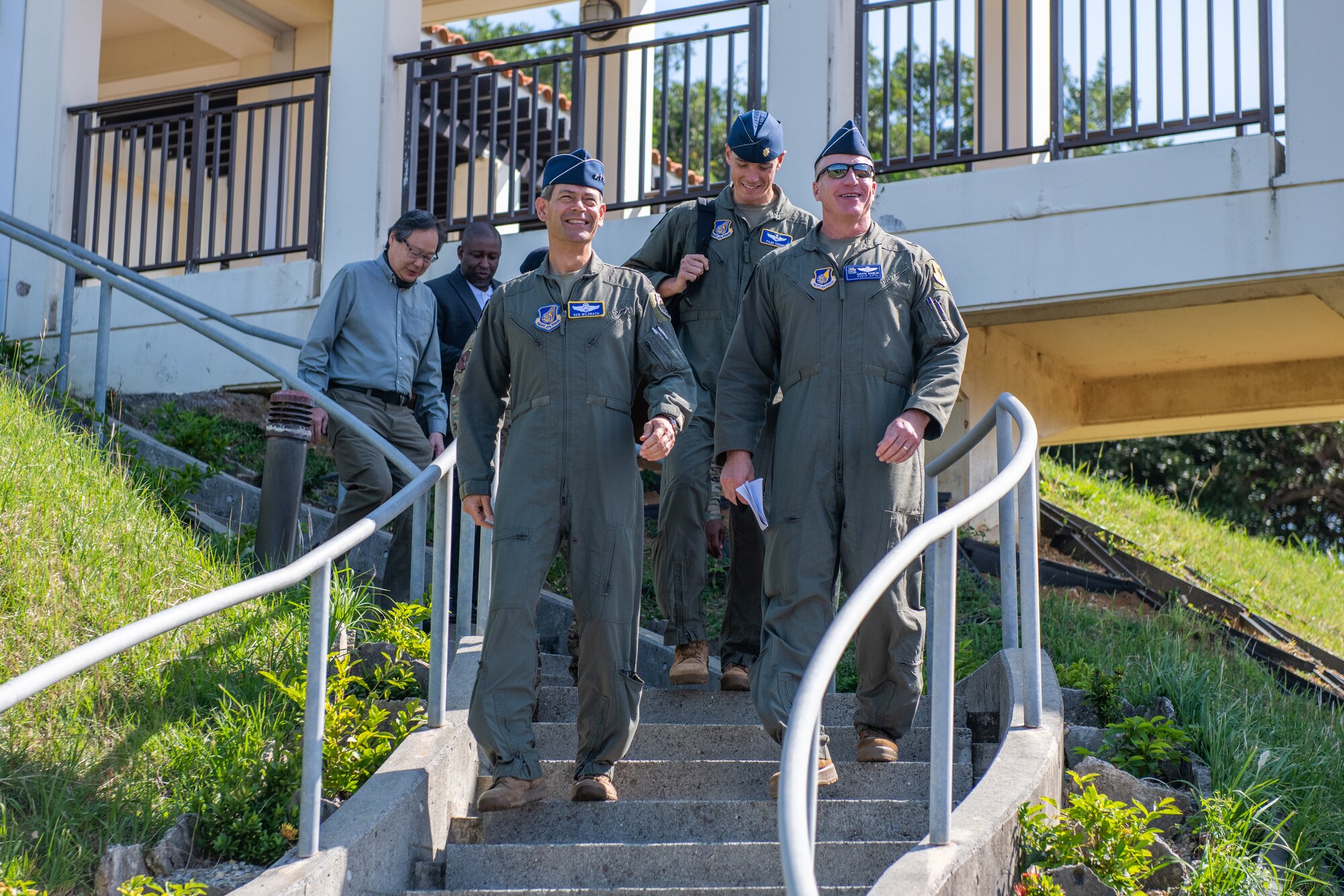 A bunch of military personnel walk down the stairs of a restaurant outdoors