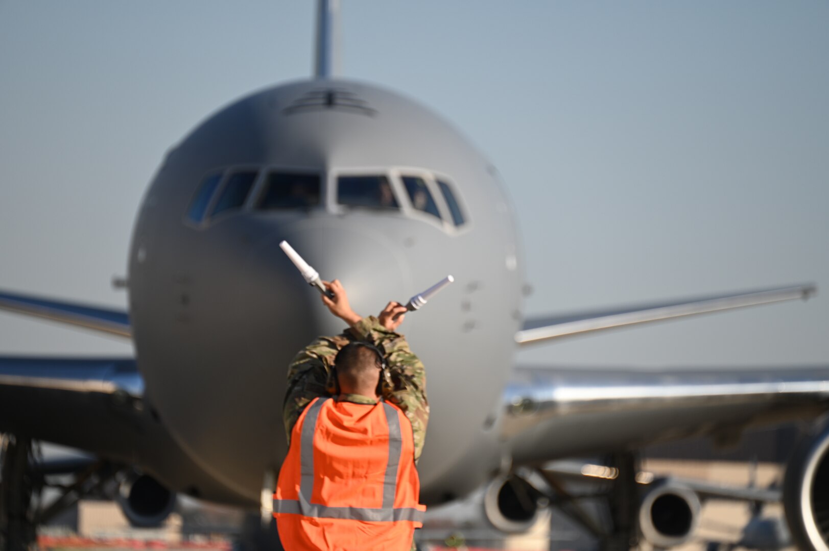 Air marshal swings batons to usher KC-46A in background