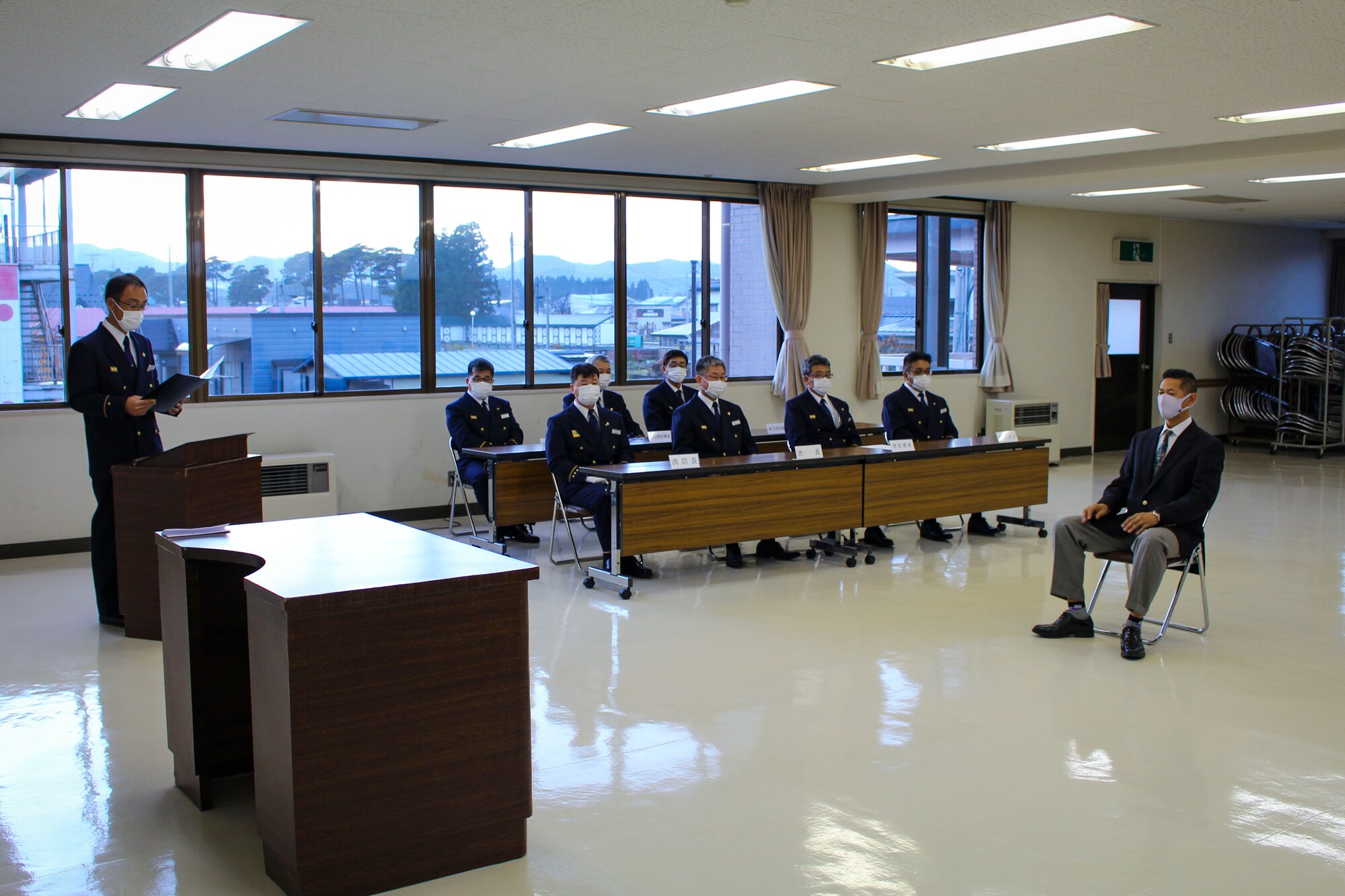 Men in uniform sit in a conference room.