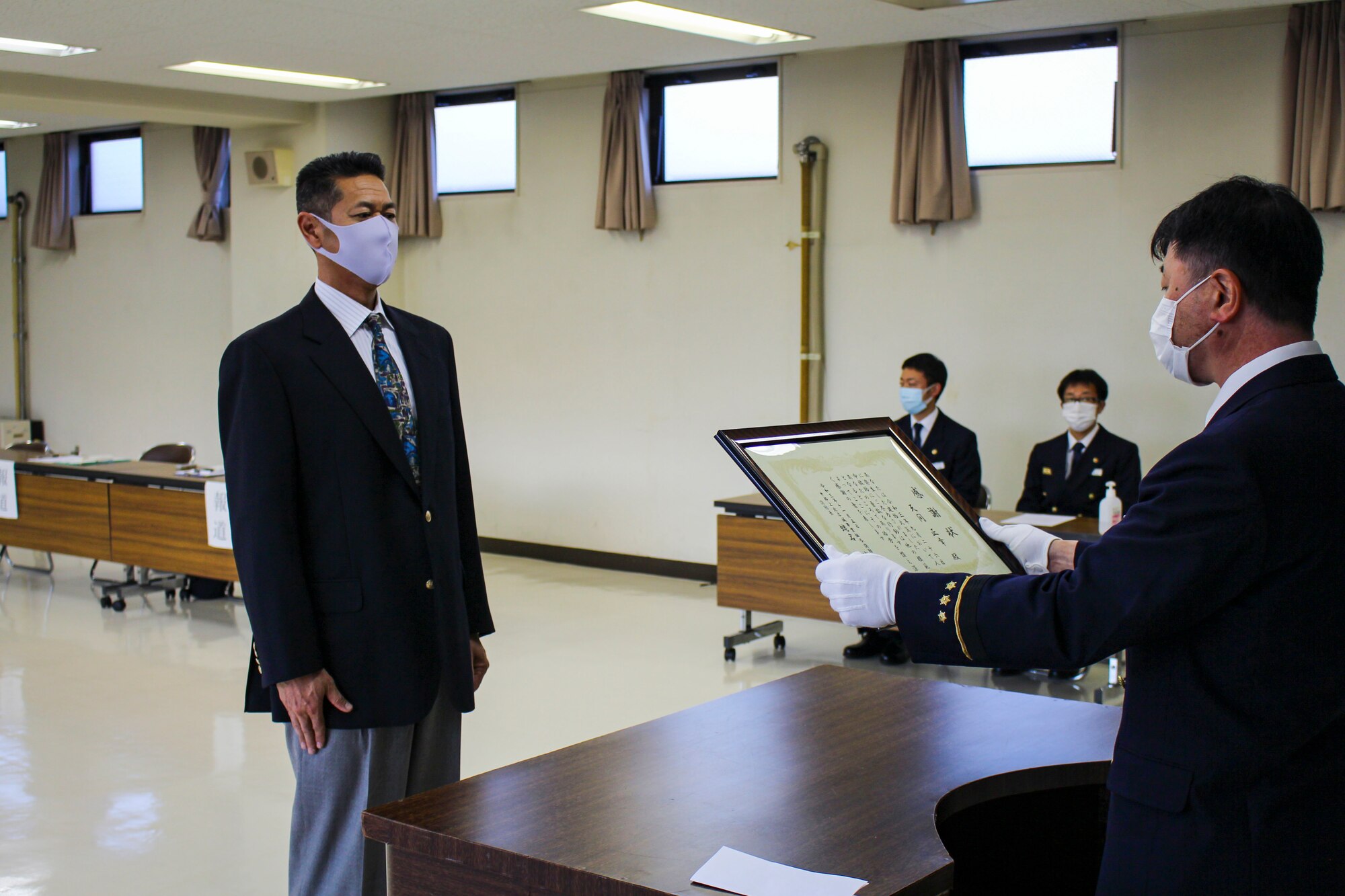 Man presents a framed document inside a fire station.
