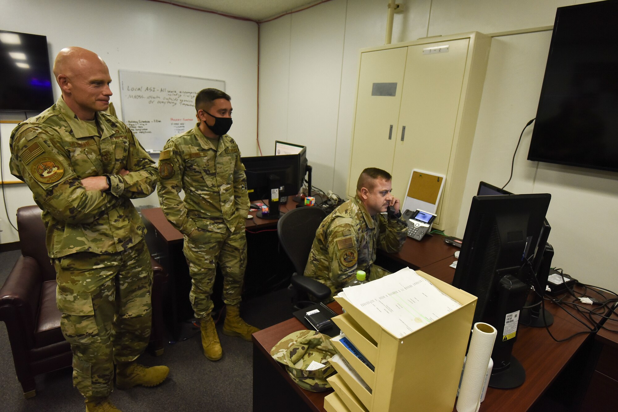 Military members stand around a computer