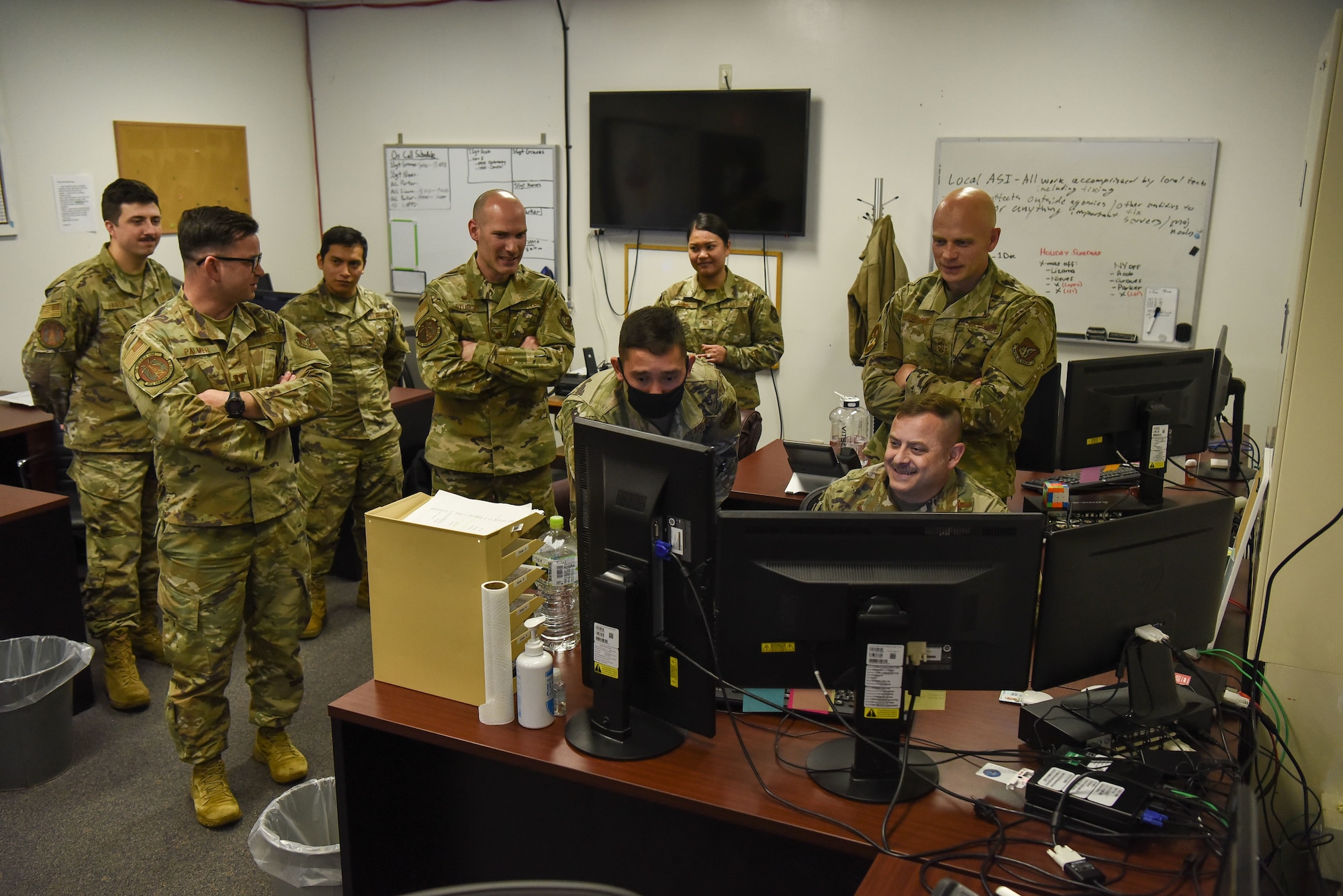 Military members stand around a computer