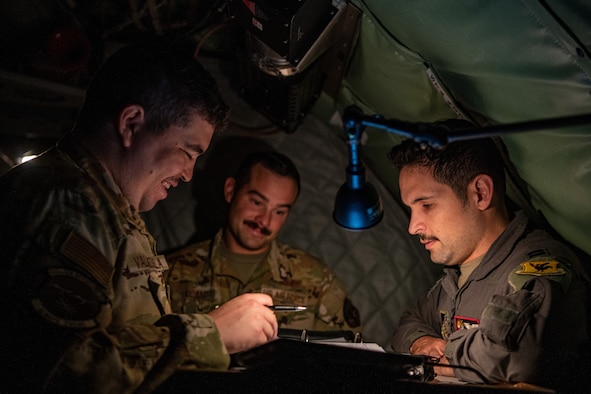 A photo of three Airman holding a briefing inside KC-135