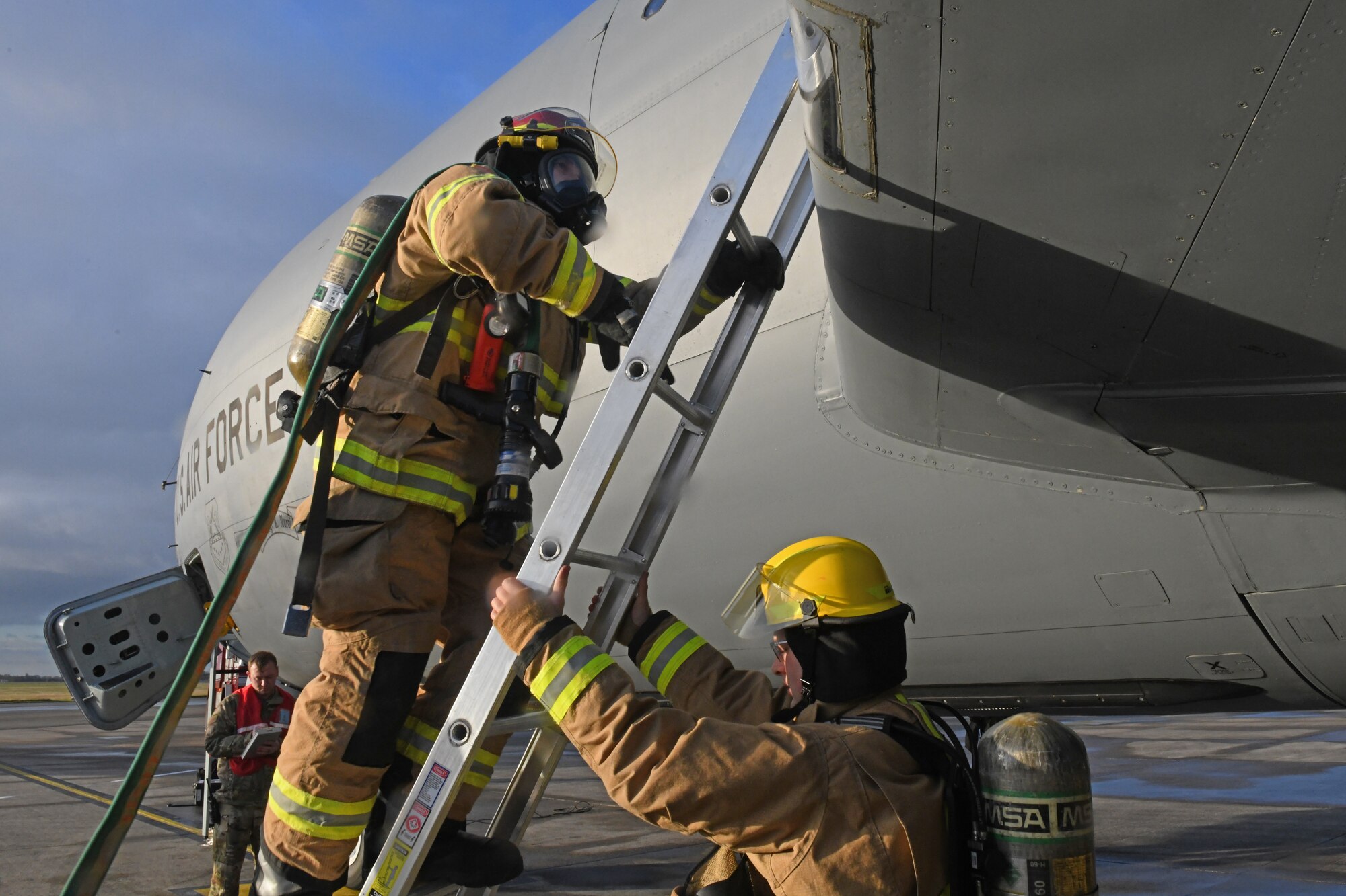 A firefighter assigned to the 100th Civil Engineer Squadronclimbs a ladder to reach the wing of a KC-135 Stratotanker aircraft during a simulated aircraft mishap at Royal Air Force Mildenhall, England, Nov. 4, 2021. The aircraft mishap simulated the aircraft skidding along the runway due to a nose landing gear failure, allowing emergency service personnel the opportunity to practice how they would respond in case of a real life incident. (U.S. Air Force photo by Tech. Sgt. Anthony Hetlage)