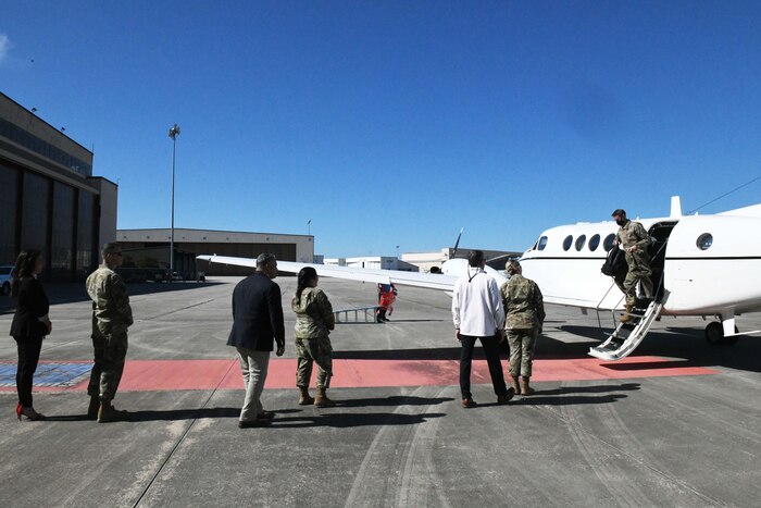 Pjoto shows people lined up outside aircraft and one person disembarking from aircraft.