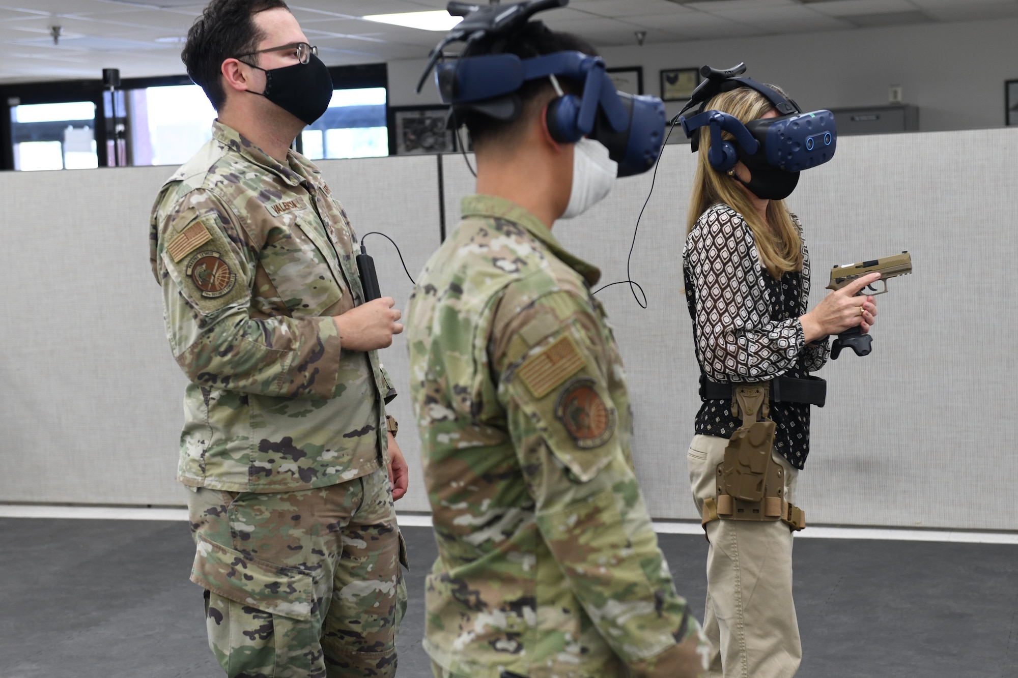 Photo shows two individuals using a VR system with a person behind them instructing.