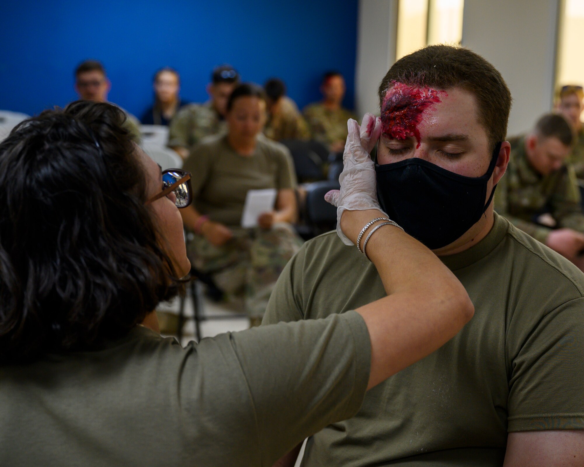 U.S. Army Spc. Stephanie Cameron, 378th Expeditionary Medical Group combat medic specialist, applies makeup to a mock injury on U.S. Air Force Staff Sgt. Brandon Warner, 378th Expeditionary Communications Squadron network technician, during a mass casualty and missile defense exercise at Prince Sultan Air Base, Kingdom of Saudi Arabia, Oct. 28 2021.