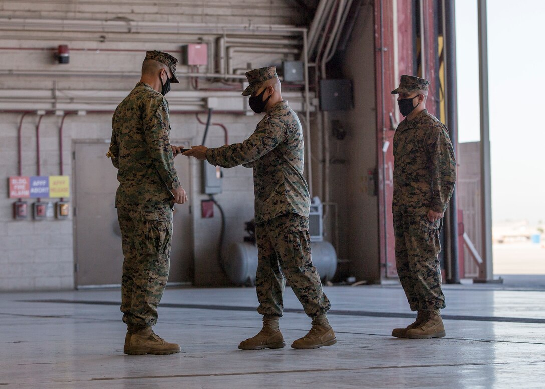 U.S. Marine Corps Sgt. Maj. Luis A. Galvez (center), offgoing sergeant major, Headquarters and Headquarters Squadron, returns the non-commissioned officer sword to the Squadron's commanding officer, Lt. Col. Robert G. Reinoehl (left), at Marine Corps Air Station (MCAS) Yuma, Ariz., Nov. 9, 2021.