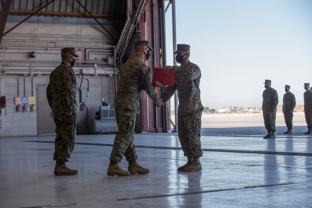 U.S. Marine Corps Lt. Col. Robert G. Reinoehl (center), commanding officer, Headquarters and Headquarters Squadron (H&HS), presents Sgt. Maj. Luis A. Galvez (right), offgoing sergeant major, H&HS, with a Meritorious Service Medal during a relief and appointment ceremony at Marine Corps Air Station (MCAS) Yuma, Ariz., Nov. 9, 2021.