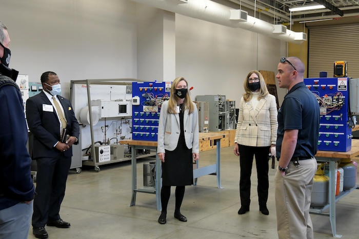 Photo shows group of people standing around work stations.