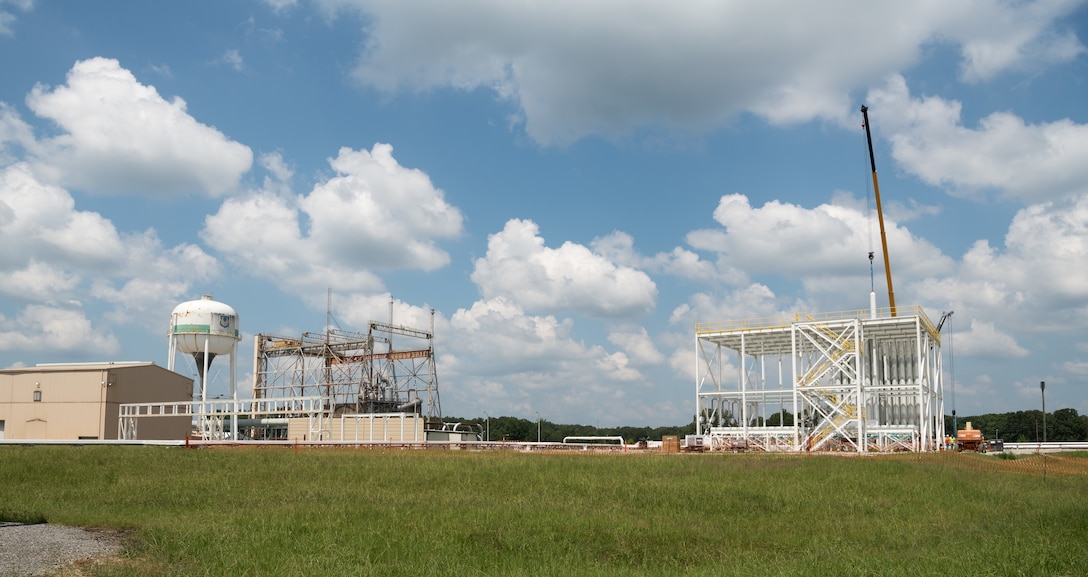A high-pressure air bottle is lifted and lowered into place in the J-5 test facility bottle farm, Aug. 26, 2021, at Arnold Air Force Base, Tenn. The tan building at left will house the test section of the large-scale, clean air, variable Mach, hypersonic test facility. (U.S. Air Force photo by Jill Pickett)