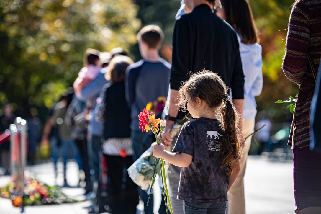 A child stands in line to give flowers.