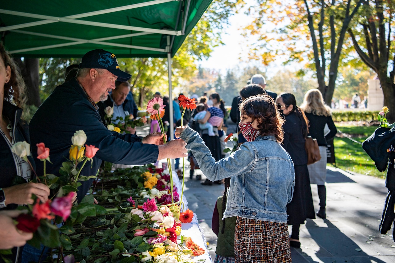 A volunteer hands a flower to a visitor at Arlington National Cemetery.