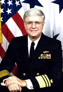 Navy Vice Admiral pictured in front of flags.