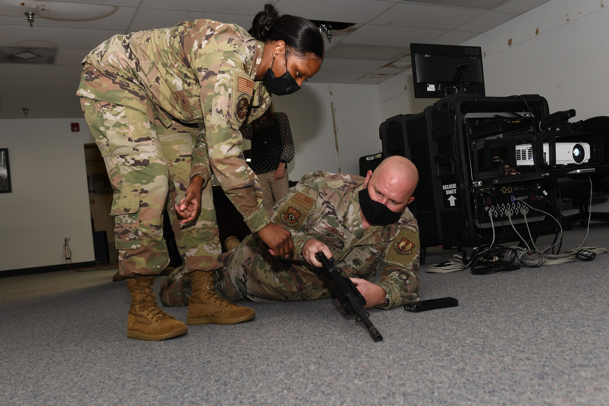 Photo shows a man on the ground learning how to work a weapons simulator.