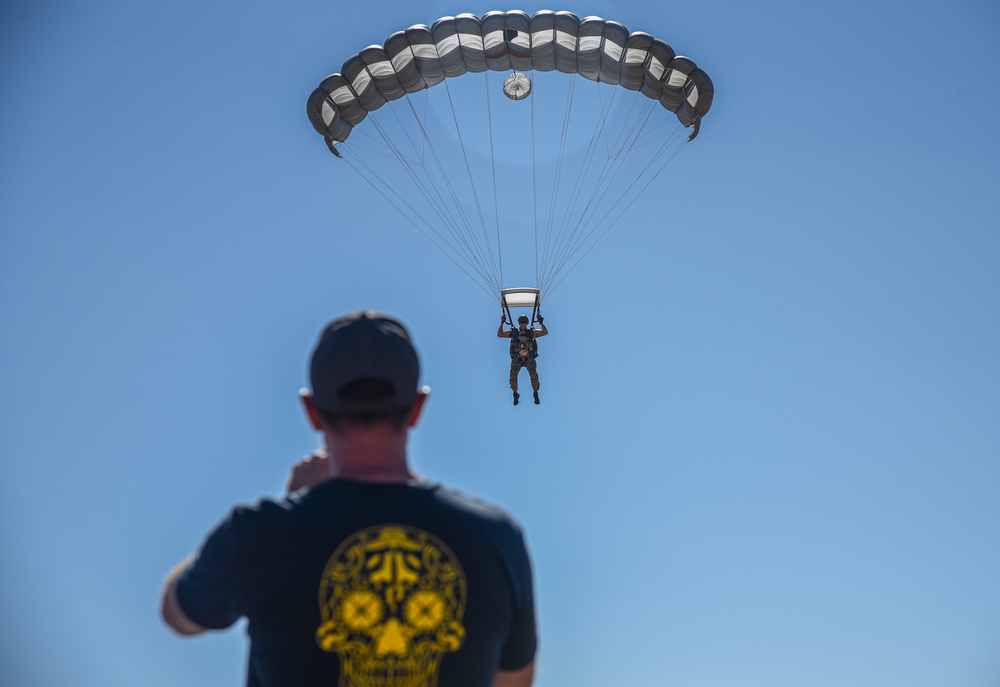 Pictured above is a man parachuting while another man video records him.