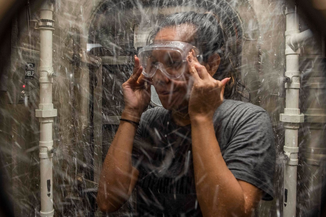 A sailor showers in a decontamination station aboard a ship.