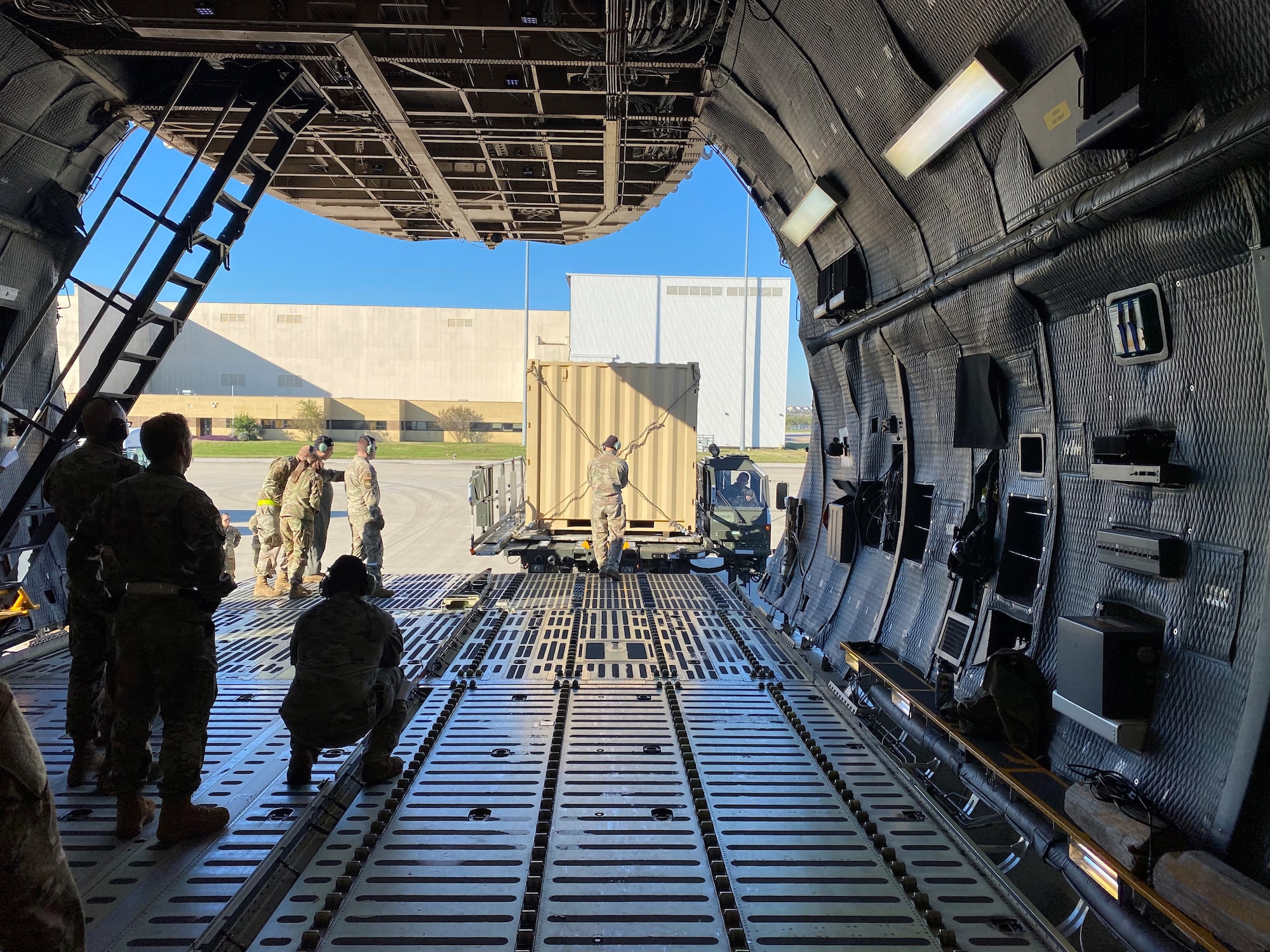 A 68th Airlift Squadron loadmaster guides a Halvorson Next Generation Small Loader driver as he pulls up to the front of a C-5M Super Galaxy aircraft during a cargo preparation and loading exercise Nov. 7, 2021 at Joint Base San Antonio-Lackland, Texas. The loader is used to transport cargo pallets to and from military and civilian cargo aircraft. (Courtesy photo by Tech. Sgt. John Shue)
