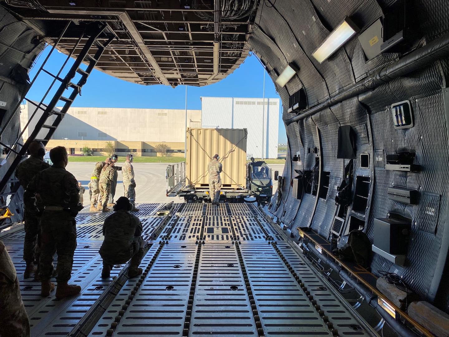 A 68th Airlift Squadron loadmaster guides a Halvorson Next Generation Small Loader driver as he pulls up to the front of a C-5M Super Galaxy aircraft during a cargo preparation and loading exercise Nov. 7, 2021 at Joint Base San Antonio-Lackland, Texas. The loader is used to transport cargo pallets to and from military and civilian cargo aircraft. (Courtesy photo by Tech. Sgt. John Shue)
