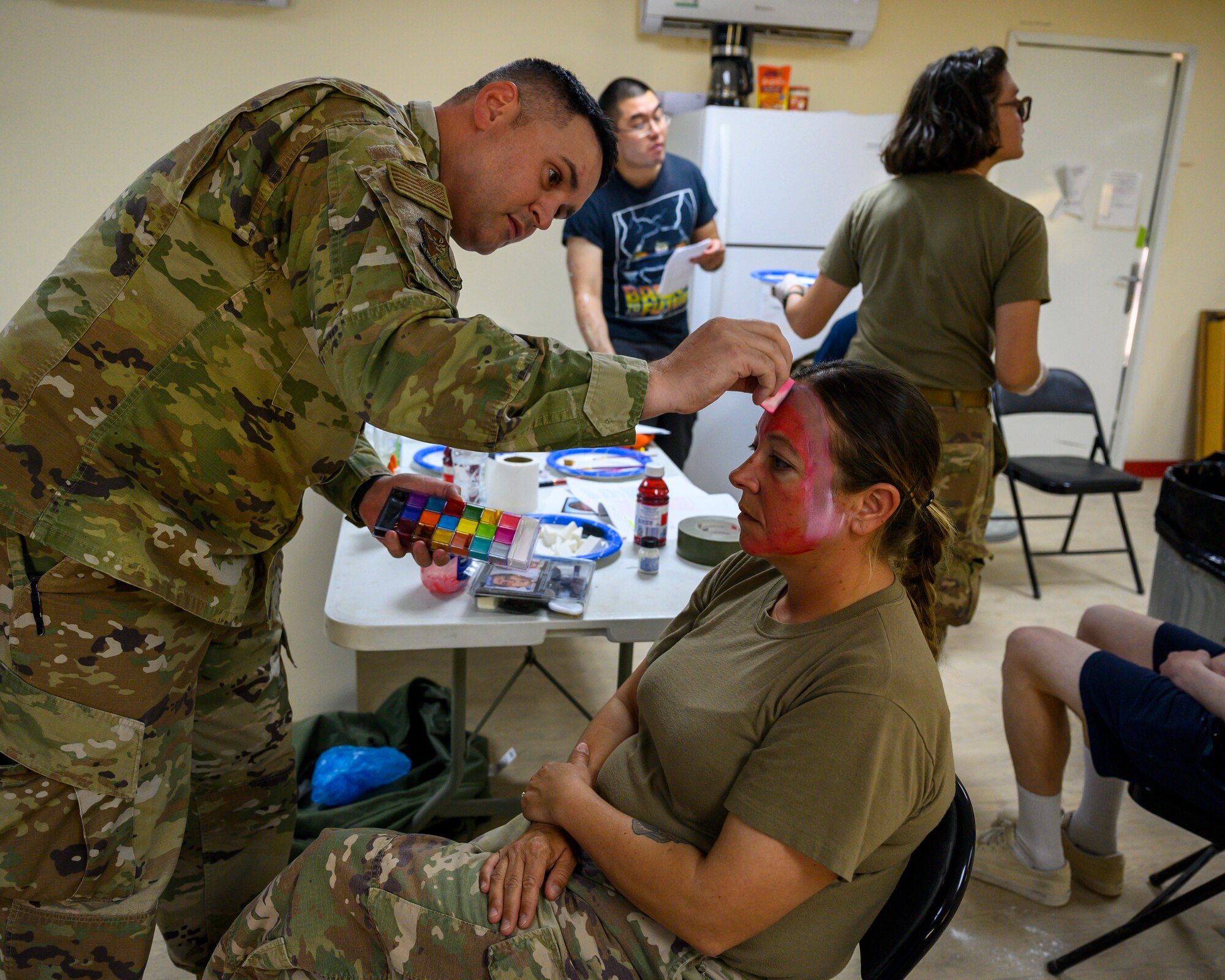 U.S. Air Force Staff Sgt. Michael Zumbrunn, 378th Host Nation Coordination Cell liaison administrator, paints U.S. Air Force Master Sgt. Danielle Barnett’s face, 378th Air Expeditionary Wing Flight Safety noncommissioned officer-in-charge, for a mass casualty and missile defense exercise at Prince Sultan Air Base, Kingdom of Saudi Arabia, Oct. 28 2021.