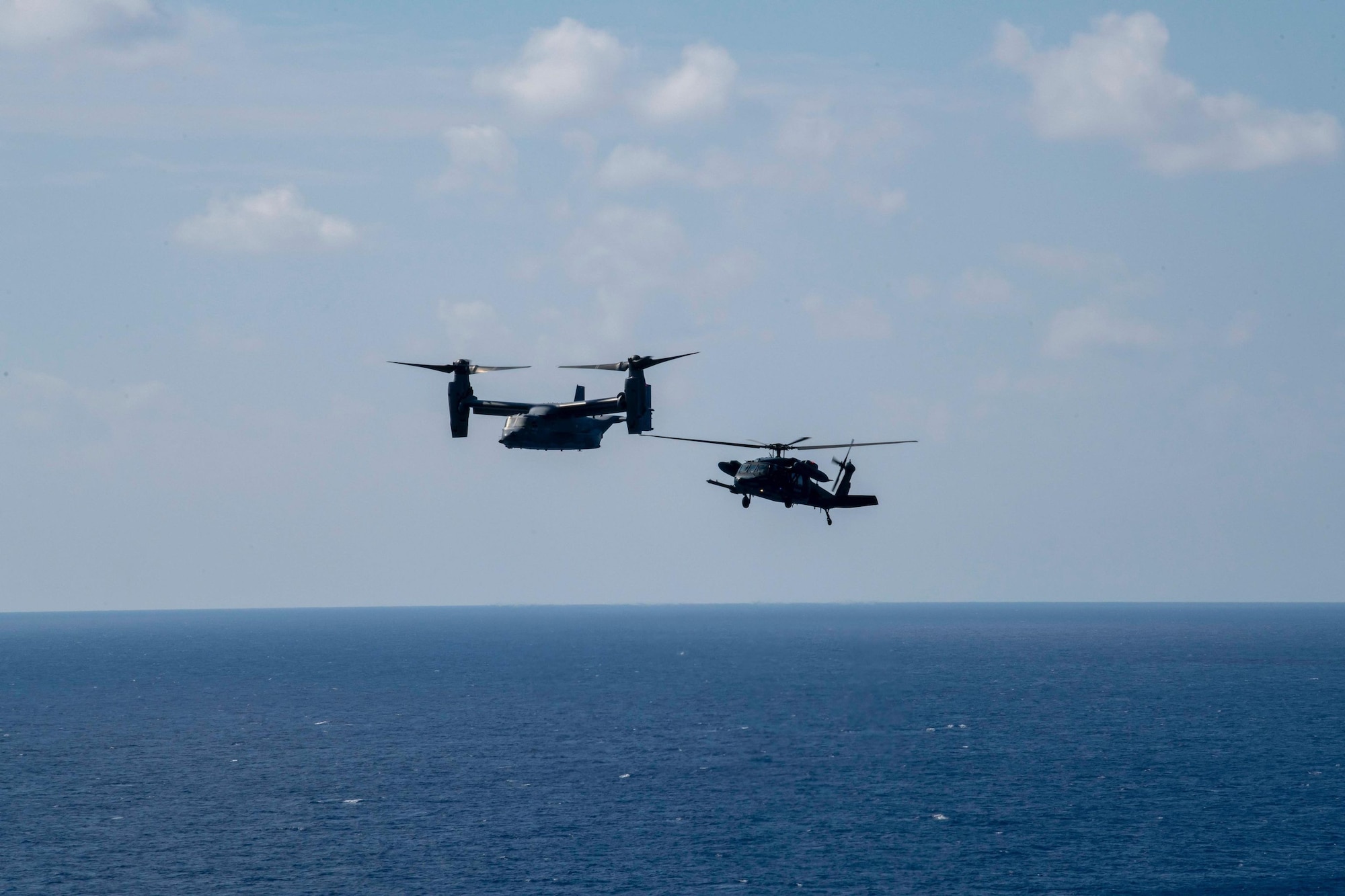 A CV-22 Osprey assigned to the 353rd Special Operations Wing flies alongside a Japanese Air Self Defense Force UH-60J assigned to Naha Air Rescue Wing on Nov 2, 2021 during a search and rescue exercise. The purpose of this training is to enhance the Japan-U.S. bilateral response capabilities to real-world emergencies. (U.S. Air Force Photo by A1C Moses Taylor)