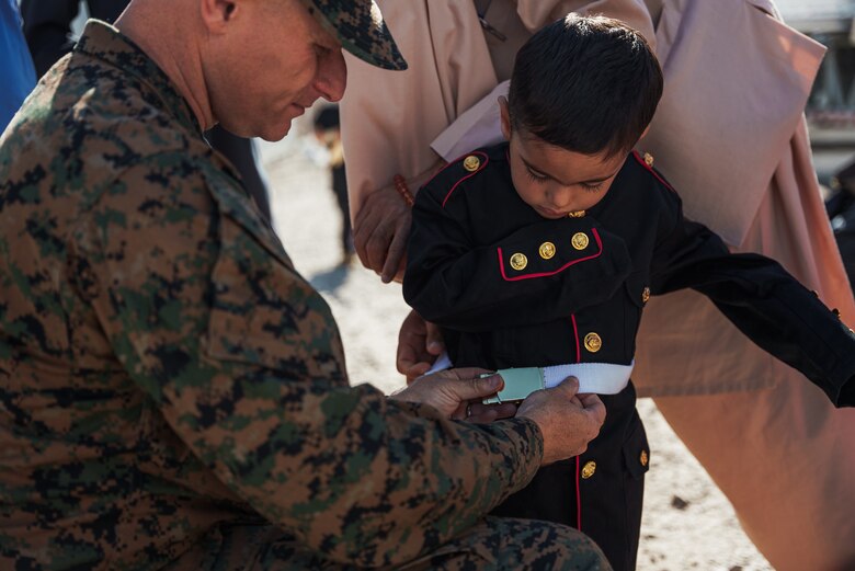 Maj. Michael Kuiper, executive officer, 3rd Battalion, 6th Marine Regiment, adjusts the belt on the Dress Blue uniform of Zabihullah, Matiullah Matie’s son, on Fort Pickett, Virginia, Oct. 24, 2021.