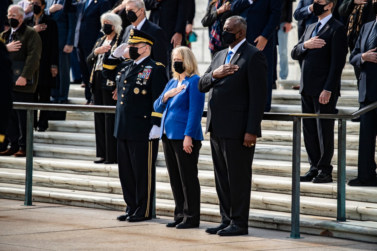 A group of people stand with their hands to their chest.