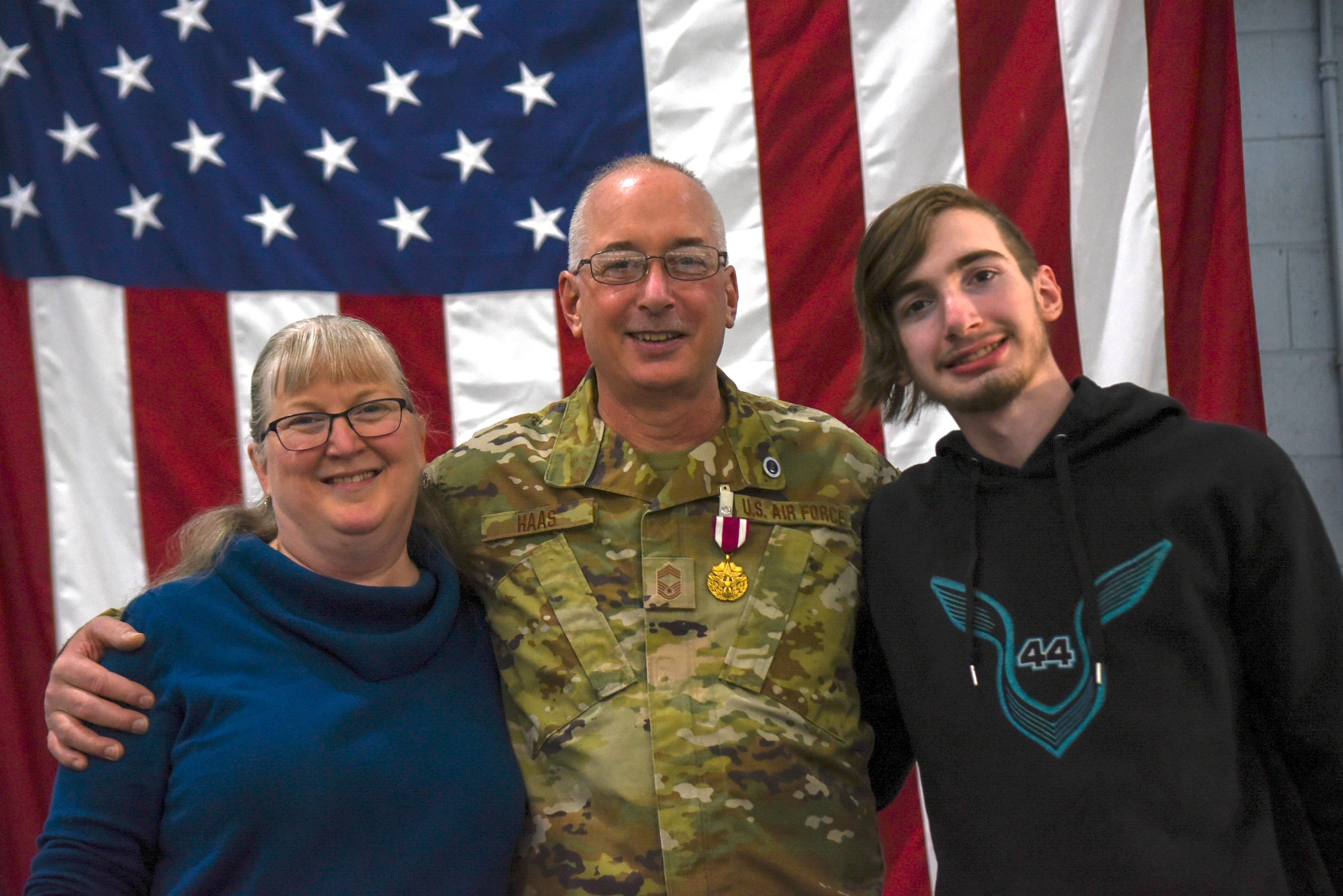 A man in an Air Force uniform poses for a picture with his wife and his young adult son.