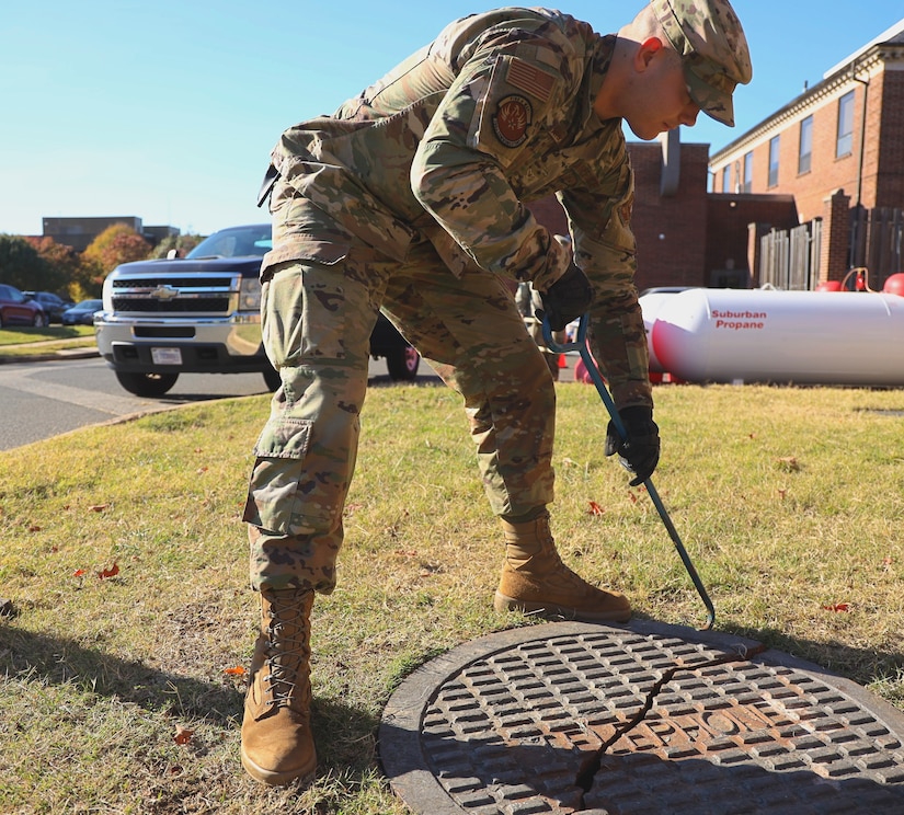 From left, U.S. Air Force Airman Austyn Norris, 794th Communications Squadron, cable antenna maintenance technician, removes a manhole cover to inspect fiber optic cables at Joint Base Anacostia-Bolling, Washington, D.C., Nov. 9, 2021.  Airmen from the 794th CS cable antenna maintenance are responsible for maintaining all physical and fiber optic structures at JBAB.
By installing and maintaining fiber optics, copper and coaxial lines, cable and antenna systems specialists, ensure the installation has efficient means of communication required to accomplish mission needs. (U.S. Air Force photo by Brian Nestor)