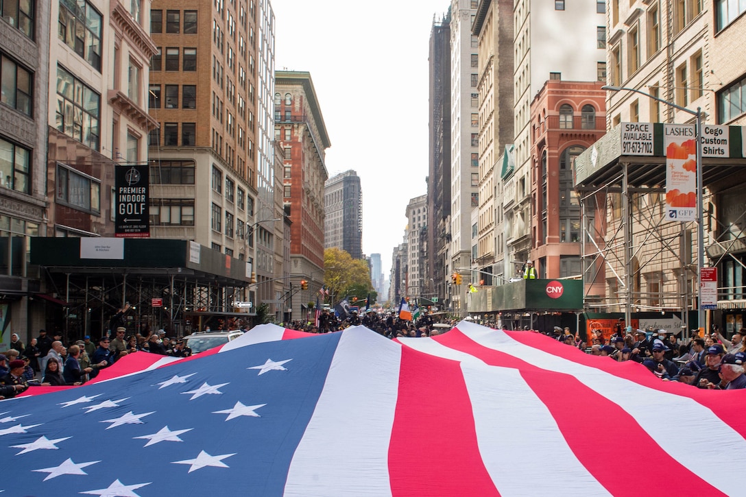 Marchers carry a huge American flag along a city street.