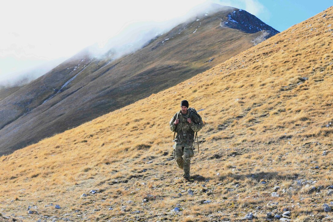 A soldier walks along a mountain range.