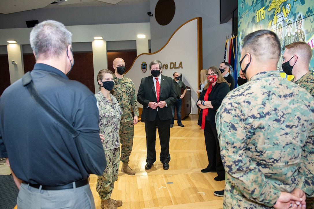 Commander Fabry in a utility uniform speaking with other military members in uniform plus one person in a black shirt and khakis.