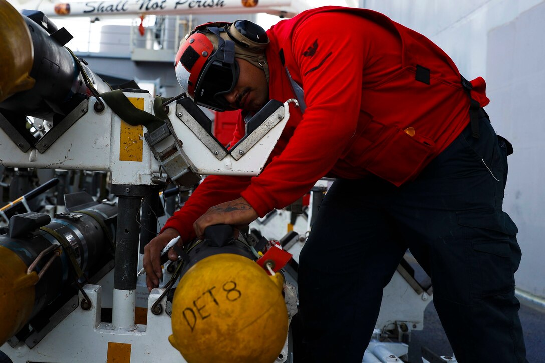 A sailor secures ordnance on a ship.