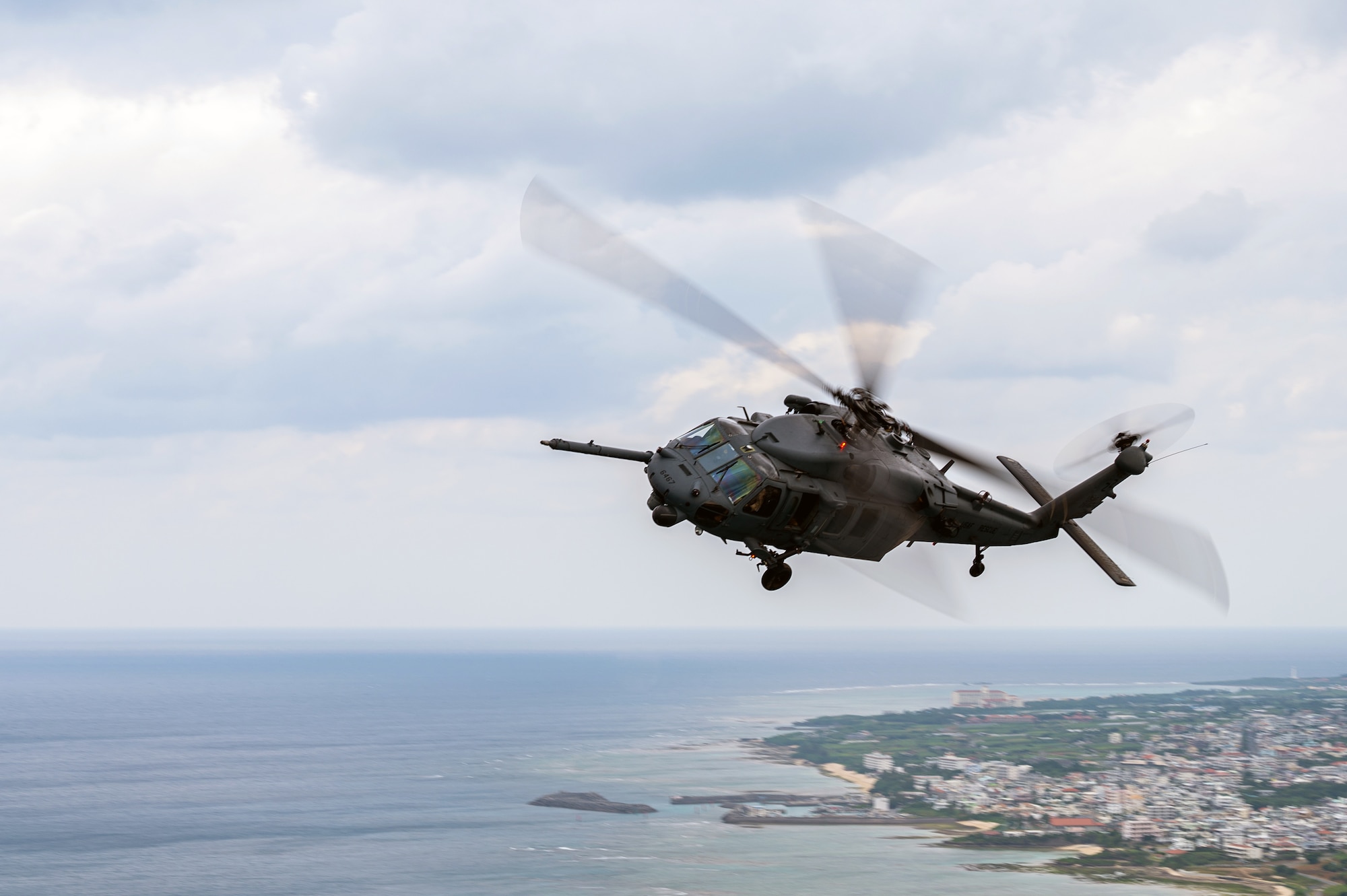 A HH-60G Pave Hawk helicopter flies over Okinawa.