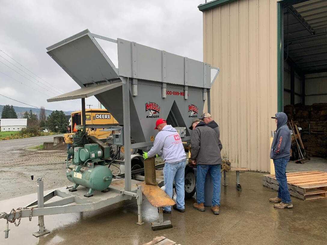Photo showing Seattle District Emergency Operations Center flood response team training Skagit County representatives on how to fill and give sandbags to residents.
