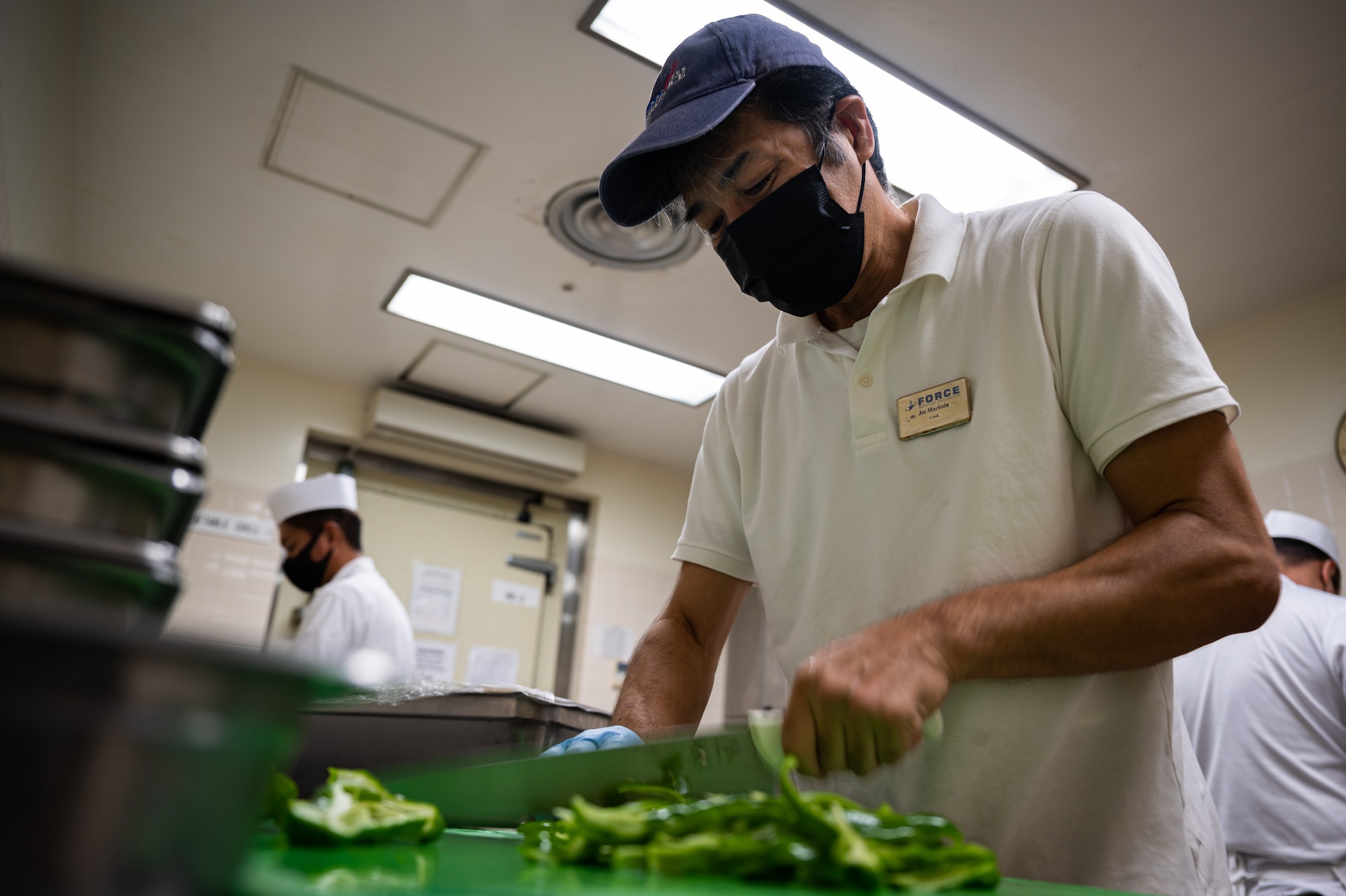 Mess attendant cuts peppers.