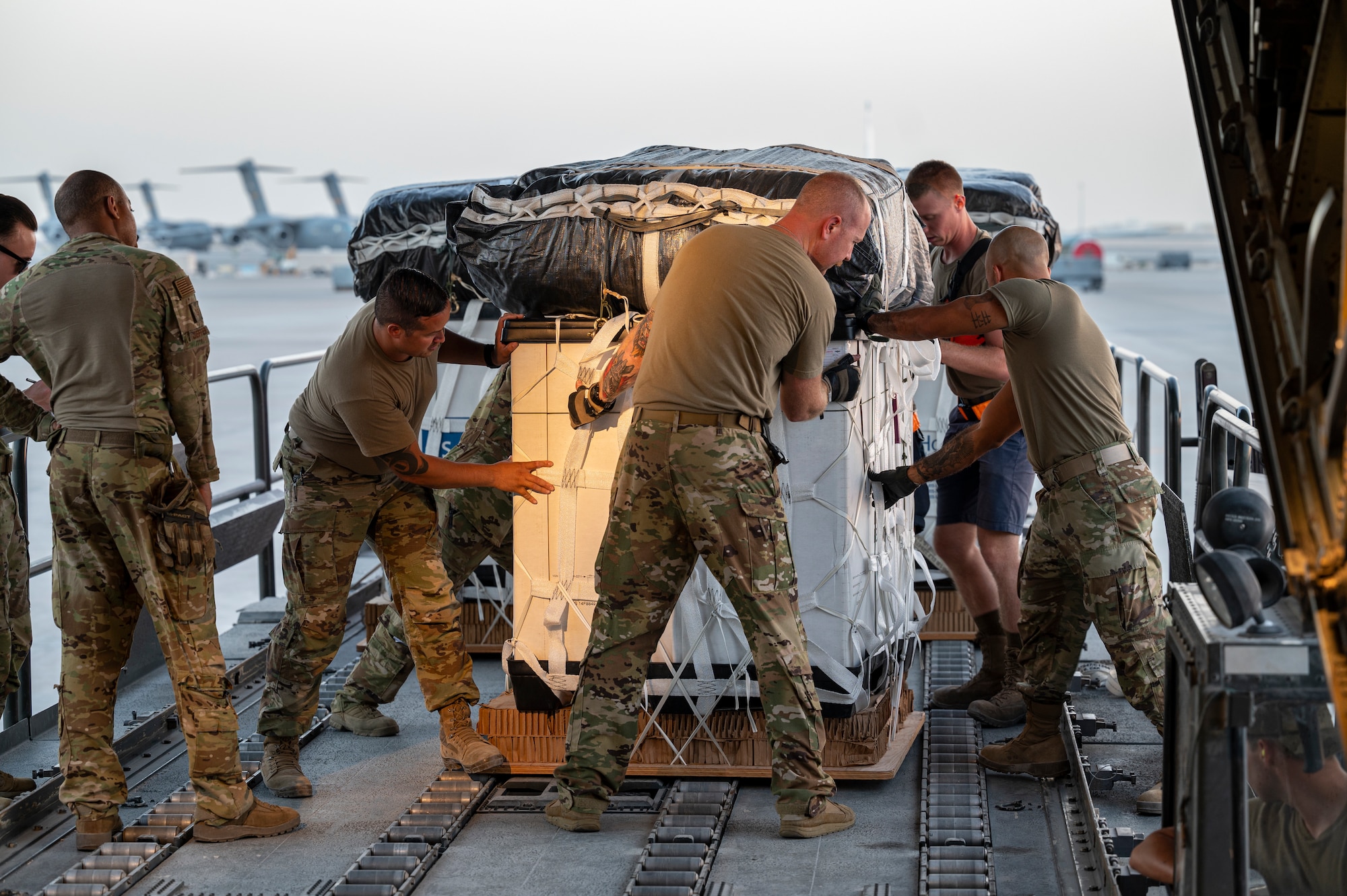 Members assigned to the 779th Expeditionary Airlift Squadron and 8th Expeditionary Air Mobility Squadron load cargo to be air-dropped into a C-130H Hercules at Al Udeid Air Base, Qatar, Oct. 31, 2021.