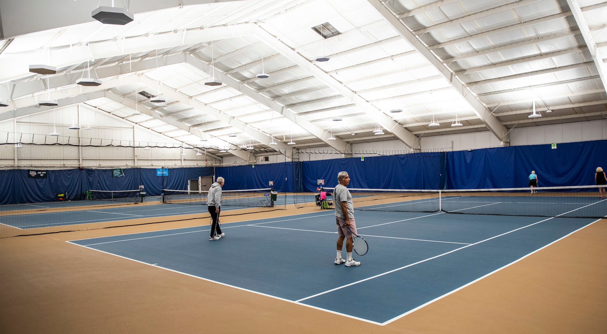 Patrons play tennis inside the base Tennis Club, Nov 1, 2021, at Wright-Patterson Air Force Base, Ohio. The club offers 4 LED lit courts to play on and several other amenities for those who need to practice. (U.S. Air Force photo by Wesley Farnsworth)
