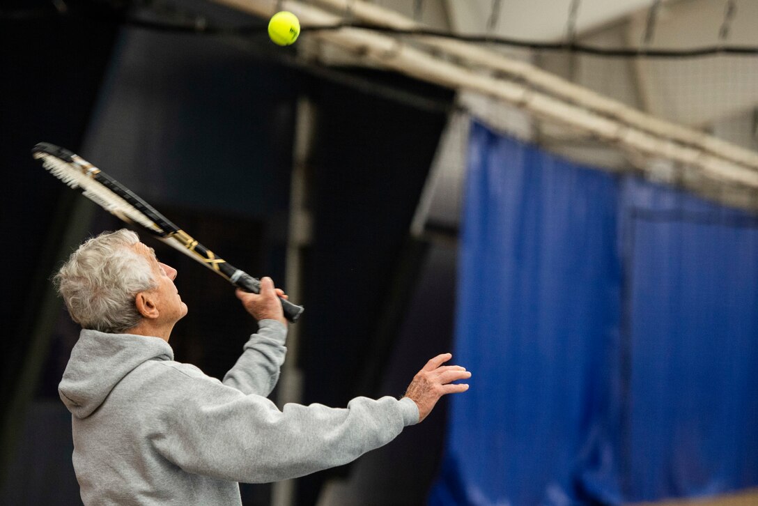 Roland Watts, serves up a tennis ball while playing tennis inside the base Tennis Club, Nov 1, 2021, at Wright-Patterson Air Force Base, Ohio. The club offers 4 LED lit courts to play on and several other amenities for those who need to practice. (U.S. Air Force photo by Wesley Farnsworth)
